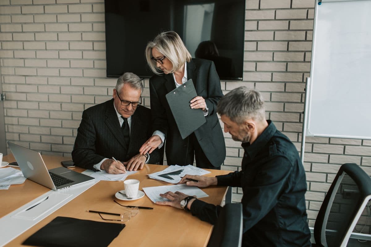 Three colleagues reviewing and signing documents in an office
